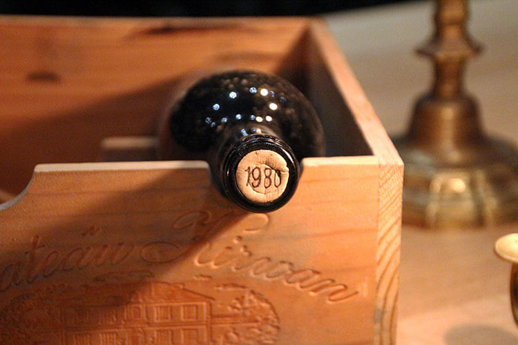 A bottle of 1980 Château Kirwan 1855 Grand Cru Classé sits in a wine box 