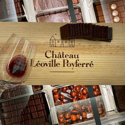 A wine glass laying flat on a Château Léoville-Poyferré board with Hasnaâ chocolats