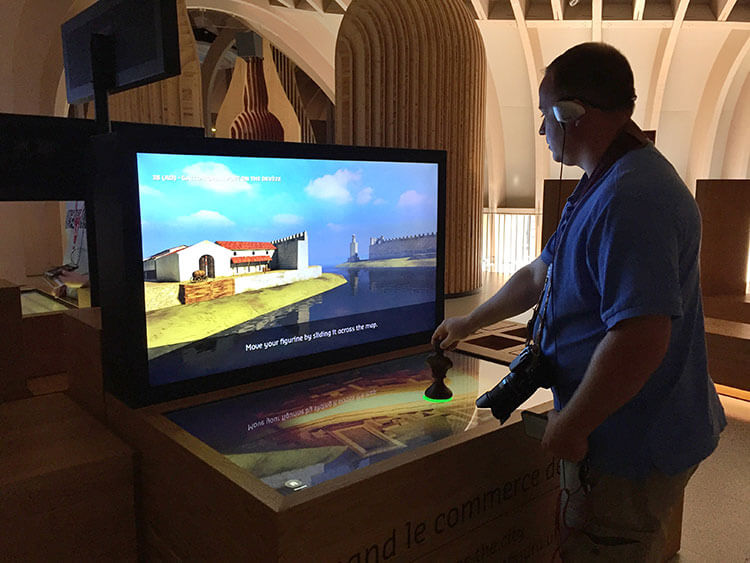 Tim uses a game piece to learn about the history of Bordeaux monuments at La Cité du Vin