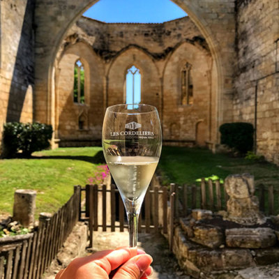 A glass of white Crémant de Bordeaux with the roofless ruined church of Les Cordeliers in the background