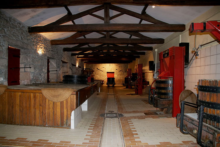 Three historical vertical presses from the 1920s line one side of the winery at Château Coutet Barsac