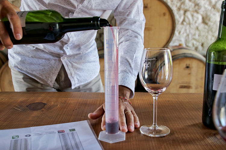 Pouring the wine into a graduated cylinder in the B. Winemaker Workshop