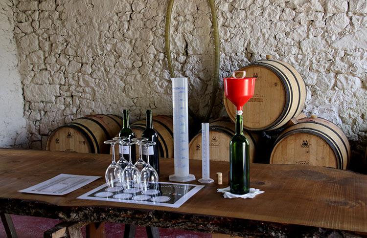 Five glasses sit on a placement with bottles of the Merlot and Cabernet and graduated cylinders for the B. Winermaker Workshop at Château Fombrauge