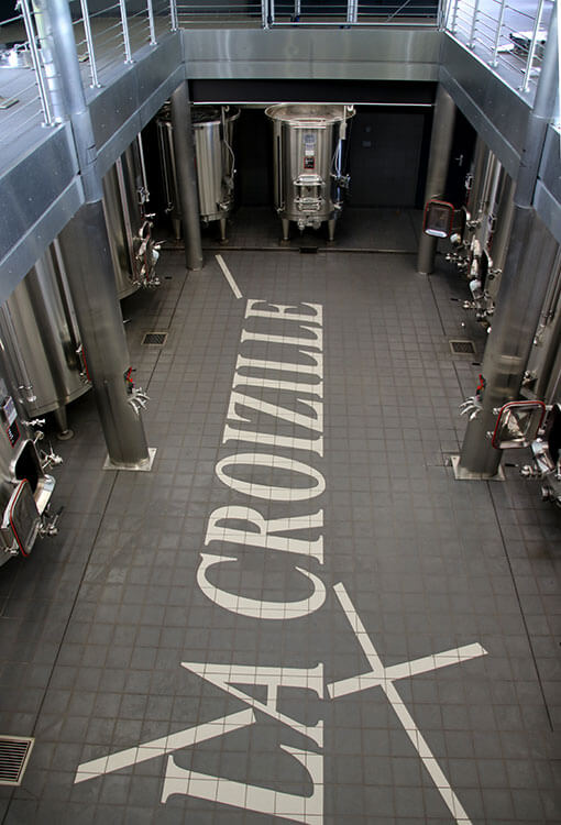 The modern vat room with stainless steel tanks and La Croizille written in the tiles of the floor at Château La Croizille