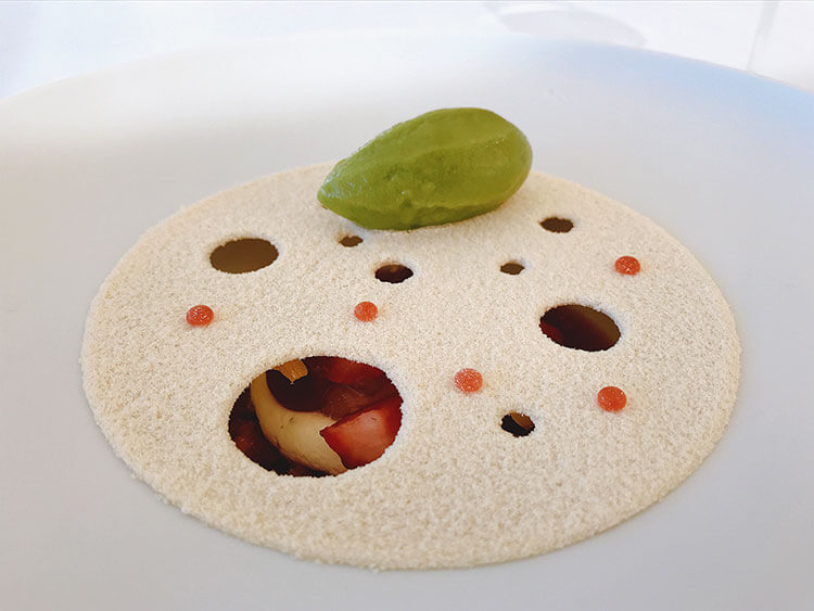 Summer red fruits topped with a flat disc of white chocolate and a herb sorbet at Restaurant Lalique at Chateau Lafaurie Peyraguey