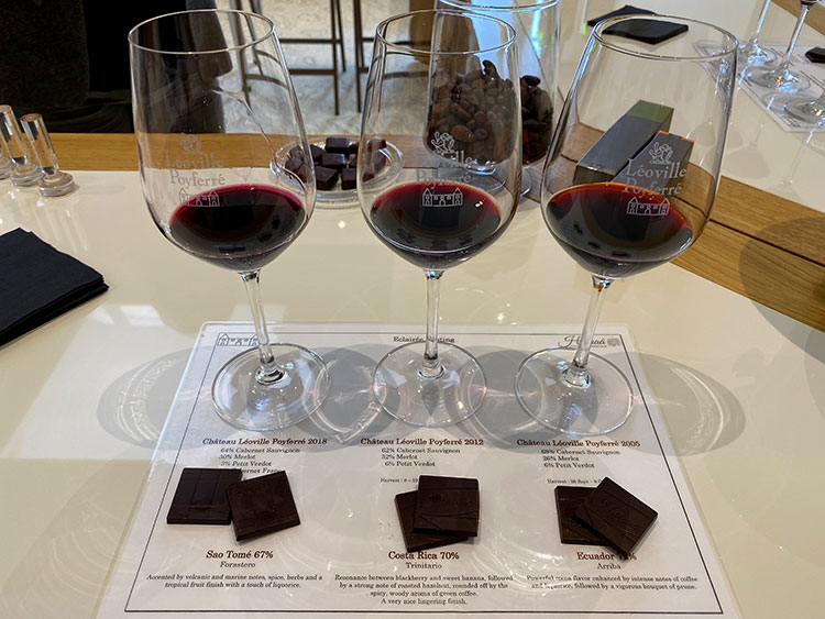 Three glasses of the 3 vintages with 2 pieces of three different origin chocolates on a placement with the wine and chocolate tasting notes at Château Léoville-Poyferré