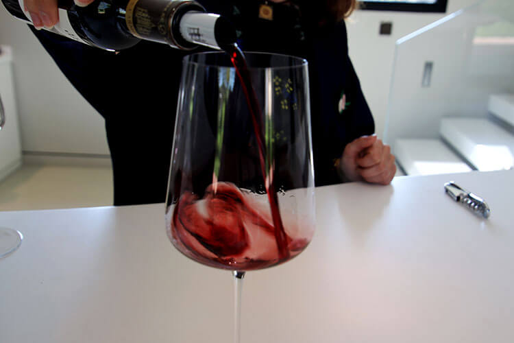 The guide pouring wine in to a glass for the tasting at Château Les Carmes Haut-Brion