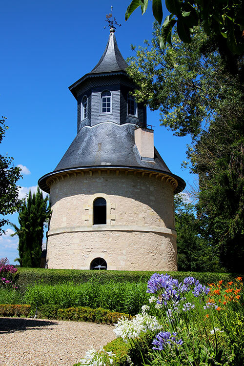 A flower lined path leads to the 18th century dovecote at Chateau de Reignac