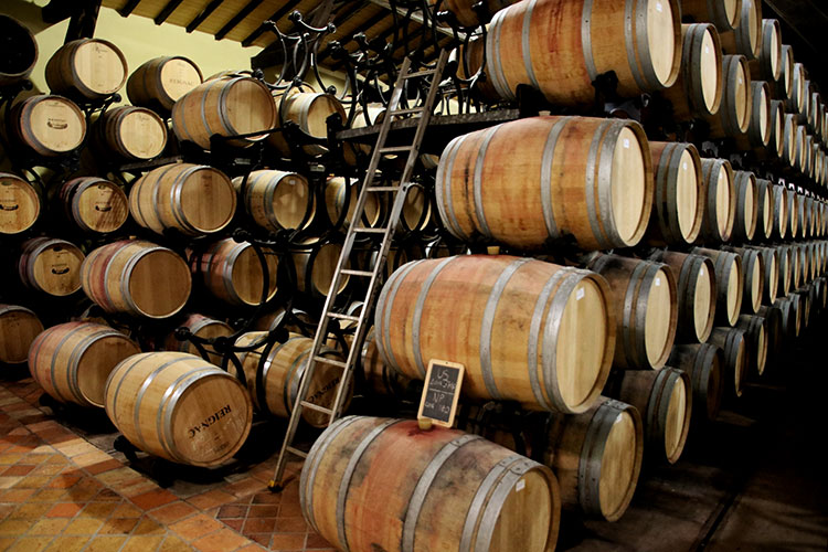 Barrels are stacked on a racking system with wheels to allow for easy turning