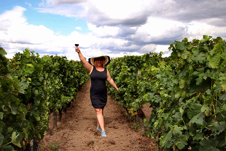 Jennifer holds up a glass of Bordeaux wine while in the vineyard in Pomerol, in the Bordeaux wine region 