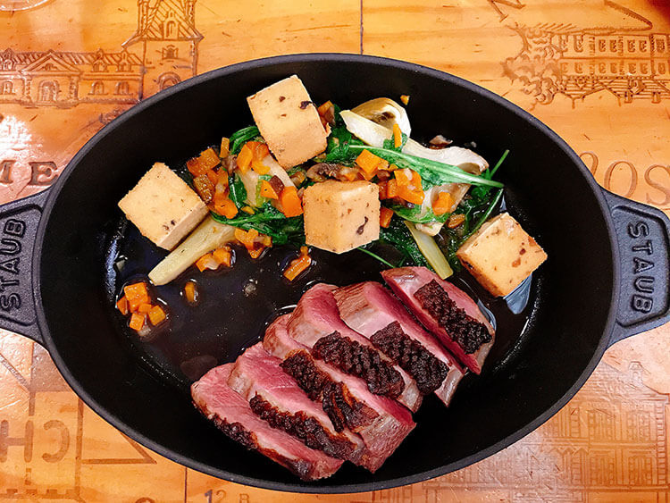 Duck breast seared and sliced served with vegetables in a Staub castiron pan