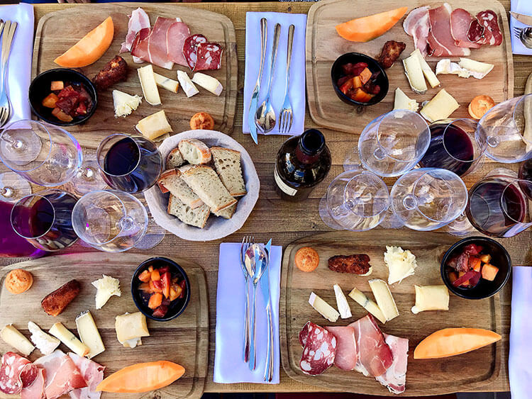 Four friends enjoying the tasting plate at Le Bis by Baud et Millet with five cheeses, melon, charcuterie and tomato salad