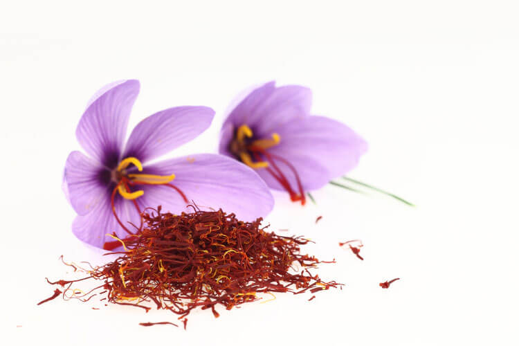 Some harvested saffron piled in front of the purpose flowers 