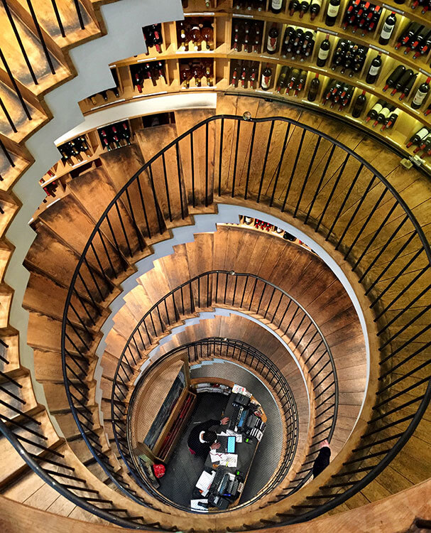 Looking down the spiral wooden staircase at L'Intendant Grands Vins de Bordeaux which is lined with over 1200 wines from the Bordeaux wine region