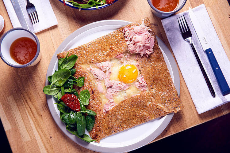 A complète galette with the sides folded in to form a square and the egg and cheese in the middle