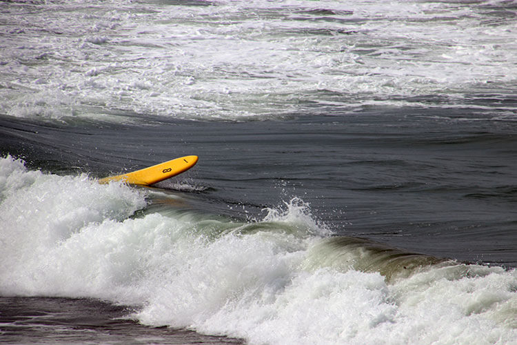 A surfboard tumbles on the waves after a surfer has fallen off