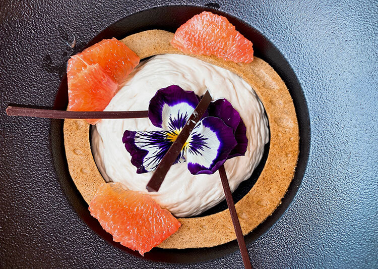 A tart pastry filled with black tea infused cream and whole pieces of grapefruit placed around the edges at Atelier de Candale