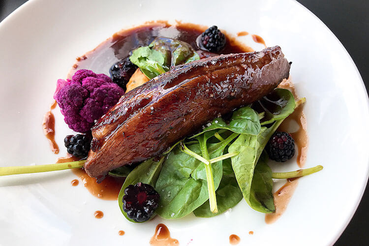 Duck breat on a bed of greens with purple cauliflower and balckberries at La Terrasse Rouge