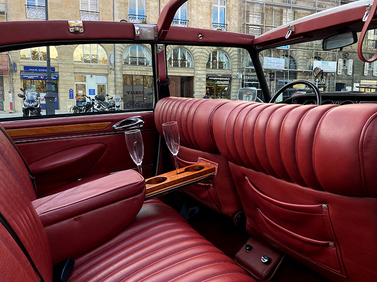 The interior with red leather seats and a mini bar to hold wine or champagne glasses 