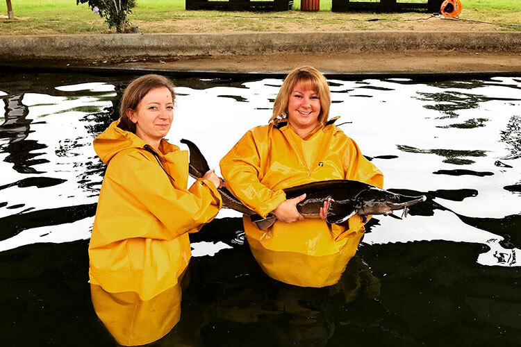 My friend Aurélie and I hold our sturgeon after catching it in the pool at Domaine de Neuvic