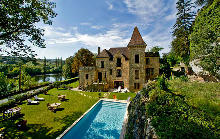 The outdoor pool with Château de la Malartrie sitting on the edge of the Dordogne River