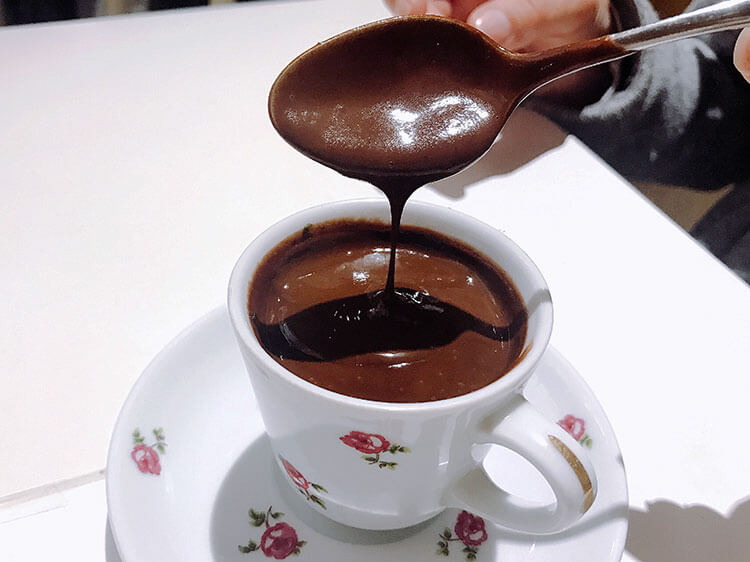The thick hot chocolate drips slowly from a spoon back in to the espresso-sized cup