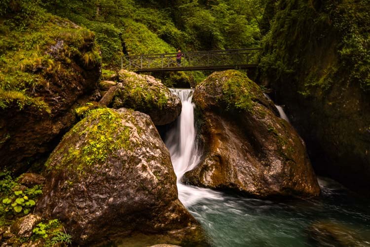 Jennifer stands on a foot bridge over a waterfall in the Gorges de Kakuetta