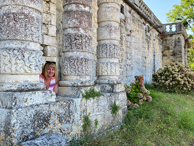 Jennifer poses in between the carved stone columns on the facade of Château de Vayres