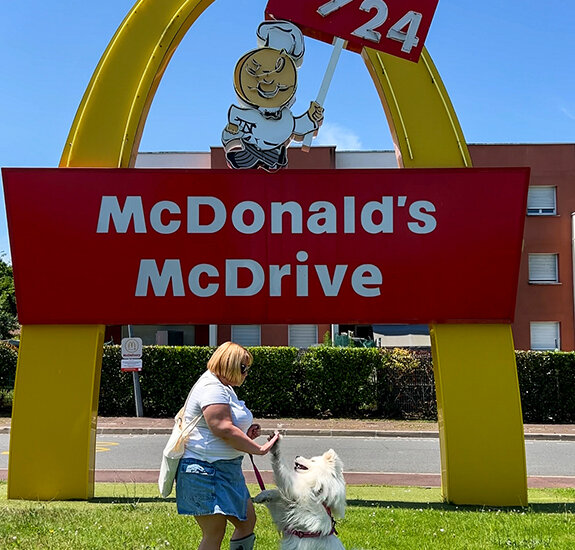 Jennifer and Coco high five in front of the vintage McDonald's Drive sign at the McDonald's V-O in Villenave-d'Ornon