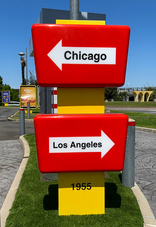 A Chicago this way and Los Angeles this way sign in the drive-thru at McDonald's V-O in Villenave-d'Ornon