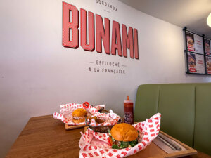 A pulled pork and pulled duck "burger" with a side of potatoes and coleslaw at Bunami