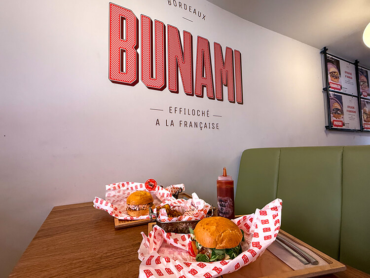 A pulled pork and pulled duck "burger" with a side of potatoes and coleslaw at Bunami