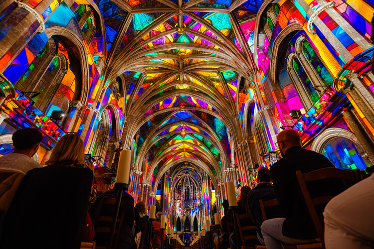 Ceiling and nave of Cathedral Saint-André in a rainbow of bright colors like pinks, yellows, and greens during LUMINISCENCE Bordeaux
