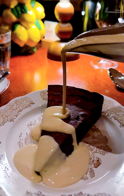 Crème anglaise is poured over a slice of fondant au chocolat cake at Brasserie Vinatier